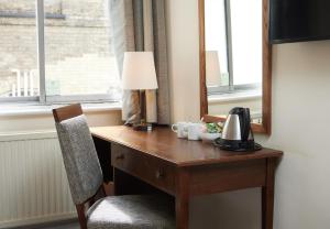 a desk with a lamp and a chair next to a window at White Hart Hotel by Greene King Inns in Braintree