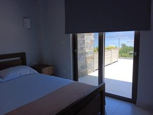 Schlafzimmer mit einem Bett und Blick auf einen Balkon in der Unterkunft Υπόσκαφα cave concept in Amolianí