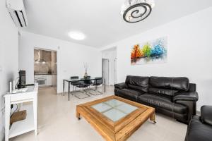 uma sala de estar com um sofá de couro preto e uma mesa em Chalet Villasol Con Piscina em Alicante