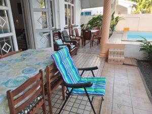a patio with chairs and a table and a pool at Villa GRAND BAIE LA CROISETTE in Grand-Baie