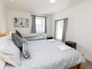 1 dormitorio con 1 cama blanca y 2 ventanas en Leisure Cottage en Kirkby Stephen