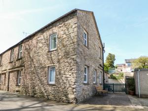 un antiguo edificio de piedra con un banco delante de él en Leisure Cottage en Kirkby Stephen