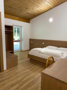 a bedroom with a bed and a table and a window at Rifugio Pian dei Ciclamini in Lusevera