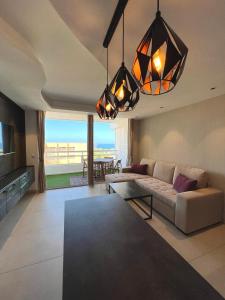 a living room with a couch and a table at The White Waves TF Holiday Apartment Las Americas in Playa Fañabe