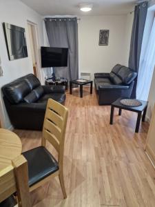 a living room with a black leather couch and a table at Coventry Home in Coventry