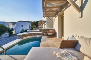 un patio trasero con piscina y una casa en Aqua Mykonos Suites - Adults Only, en Tourlos