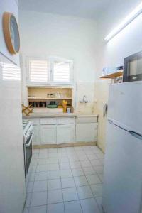 uma cozinha com armários brancos e um frigorífico branco em One bedroom and a patio-Is all about the location! em Tel Aviv