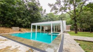 a swimming pool with a pavilion around a house at Palmstone Retreat in Kitulgala