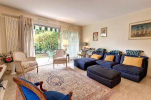 een grote woonkamer met een blauwe bank en stoelen bij HENRI CAMILLE REAL ESTATE - GOYA - One bedroom close center in Cannes