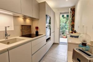 een keuken met witte kasten, een wastafel en een raam bij HENRI CAMILLE REAL ESTATE - GOYA - One bedroom close center in Cannes