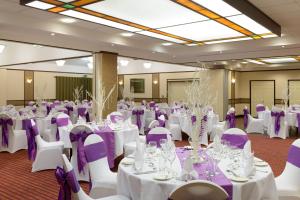 un salón de banquetes con mesas blancas y sillas moradas en Cranfield Management Development Centre, en Cranfield