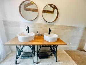 dois lavatórios sobre uma mesa de madeira com dois espelhos em Gîte l’Occitanette em Saint-Blancard