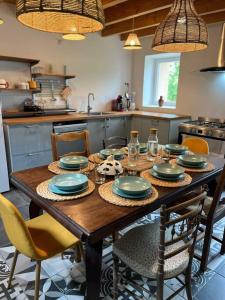 uma cozinha com uma mesa de madeira com placas e cadeiras em Gîte l’Occitanette em Saint-Blancard