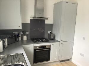 uma cozinha com armários brancos e um forno com placa de fogão em 5a Plantation Road em Stornoway