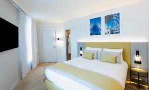 - une chambre avec un grand lit blanc et des oreillers jaunes dans l'établissement Crowne Plaza - Marseille Le Dôme, à Marseille