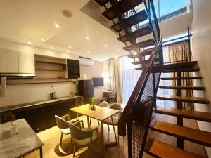 a living room with a staircase and a table and chairs at Oxy suites 2-02 at Shop House Meisterstadt Pollux Habibie in Batam Center