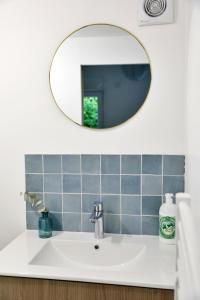 ein Bad mit einem Waschbecken und einem Spiegel in der Unterkunft Gîte Les amoureux de la Baie in Favières
