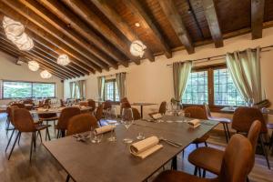 uma sala de jantar com mesas, cadeiras e janelas em Alpine Forest Hotel em Champoluc