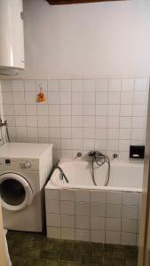 een badkamer met een bad en een wasmachine bij Eleonora in Koper