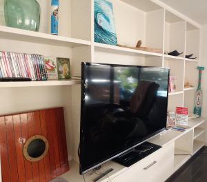 a large flat screen tv sitting on a shelf at Award Winning Beach Front Retreat in Frankston