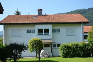 una grande casa bianca con tetto rosso di AlpenGlück – **** Ferienwohnung a Siegsdorf
