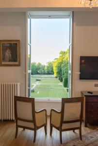 a living room with a large window with a view of a tennis court at Château du Rondon in Olivet