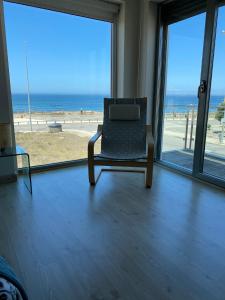 a chair in a room with a view of the beach at Angeiras Beach House - Porto - Villa by the Sea in Lavra