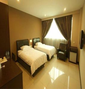 une chambre d'hôtel avec deux lits et une chaise dans l'établissement Capital O 90767 Rail Hotel, à Keluang