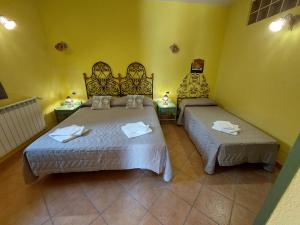 2 camas en una habitación con paredes amarillas en Borgo Gaggi p1 piano terra, en Gaggi