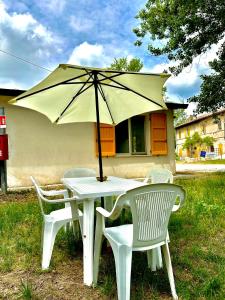 een witte tafel en stoelen met een parasol bij “Il Casale Nel Bosco…Al Mare” in Lido di Savio