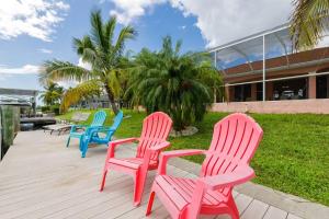 vier kleurrijke stoelen op een terras voor een gebouw bij Villa Maxos - Boaters dream 4br/3 bath pool / spa in Cape Coral