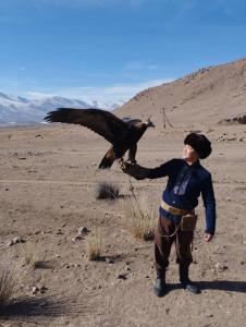 Ein Mann mit einem Vogel am Arm in der Wüste. in der Unterkunft Homestay JAISEL in Bischkek
