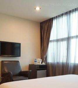 um quarto de hotel com uma cama e uma cadeira e uma janela em Capital O 90767 Rail Hotel em Keluang