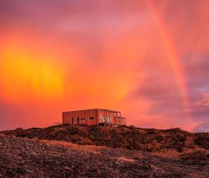 Ein Gebäude auf einem Hügel mit Regenbogen am Himmel in der Unterkunft where the ocean meets land in Ramberg
