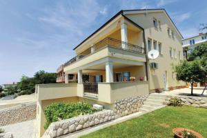 a large yellow house with a stone wall at APP Mirela 3 in Novi Vinodolski
