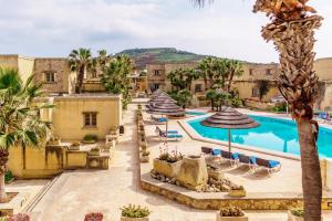 uma imagem de um resort com piscina e palmeiras em Villagg tal-Fanal em Għasri