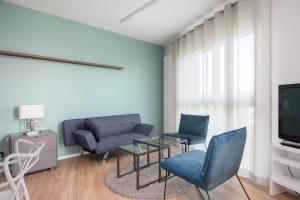 uma sala de estar com um sofá e cadeiras e uma televisão em Okopowa Blue Apartment em Varsóvia