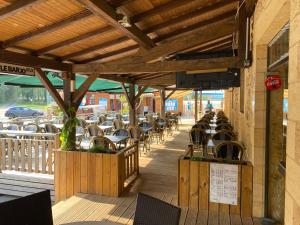 eine Terrasse mit Tischen und Stühlen an einem Gebäude in der Unterkunft Camping de Maillac in Sainte-Nathalène