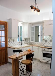 a kitchen with white cabinets and a wooden table at Lithi Stylish Apartments- Eco Luxury Suite in Tripití