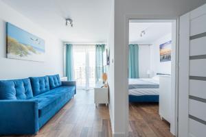 sala de estar con sofá azul y cama en Horyzont Apartamenty- Bałtycka 7AB- ŚNIADANIA en Kołobrzeg