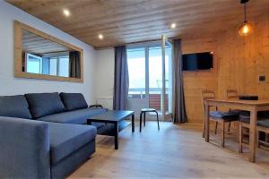 un soggiorno con un divano e un tavolo di Douillet 33 m² piscine et sauna - 6 pers a LʼAlpe-dʼHuez