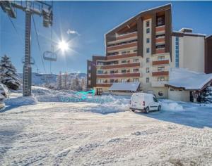 ein Auto, das im Schnee vor einem Gebäude parkt in der Unterkunft Douillet 33 m² piscine et sauna - 6 pers in Huez