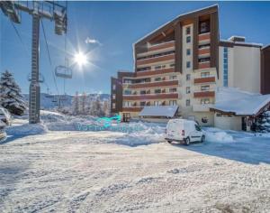 un'auto parcheggiata nella neve di fronte a un edificio di Douillet 33 m² piscine et sauna - 6 pers a LʼAlpe-dʼHuez