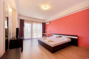 a bedroom with a bed with a red wall at SeaX Stay Apartment - free parking in Mamaia Sat/Năvodari
