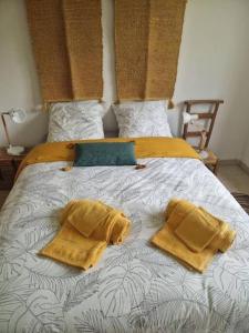 - un lit avec 2 oreillers jaunes au-dessus dans l'établissement Le Logis Maupassant, à La Rivière-Saint-Sauveur