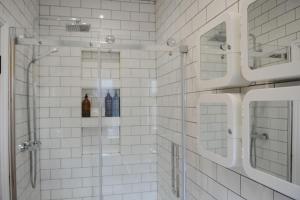 a white tiled bathroom with a shower and two mirrors at The Snug in Riccall +38 photos
