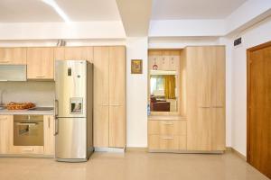a kitchen with a refrigerator and wooden cabinets at SeaX Stay Apartment - free parking in Mamaia Sat/Năvodari