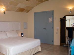 1 dormitorio con cama blanca y puerta azul en RifugioAzul & RifugioAzul Boutique en Ciutadella