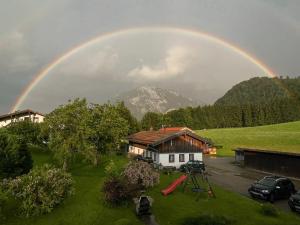 a rainbow over a yard with a house and a playground at Maurerhof in Ruhpolding