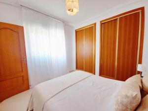 um quarto com uma cama, portas de madeira e uma janela em ATICO CON BARBACOA em Torrevieja